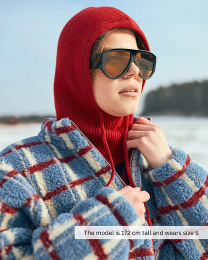 Model wearing a Merino Wool Fleece Jacket in Shadow Blue with a red hood, perfect for transitional weather.