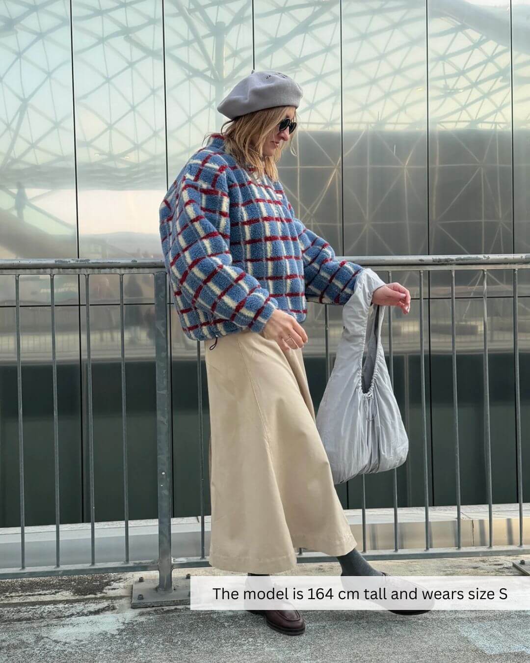 Model wearing a Merino Wool Fleece Jacket in Shadow Blue, styled with a light-colored skirt and hat.