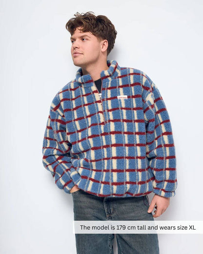 Model wearing a Merino Wool Fleece Jacket in Shadow Blue with a plaid design, featuring a zipper and stand-up collar.