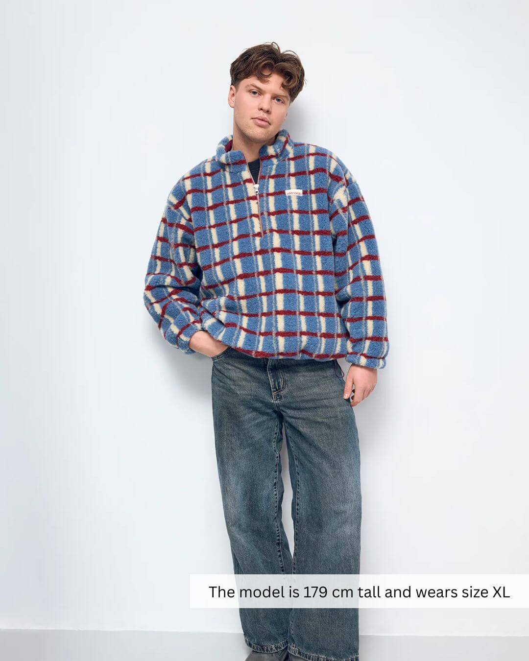 Model wearing a Merino Wool Fleece Jacket in Shadow Blue with a plaid design, featuring a zipper and stand-up collar.