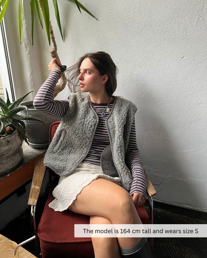 Woman sitting outdoors wearing a merino wool vest, breathable merino wool vest for casual outfits