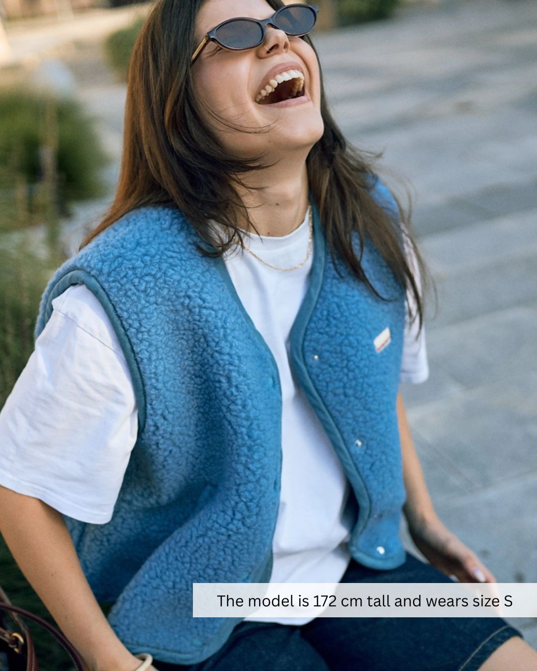 Woman wearing a blue merino wool vest layered over a shirt, breathable merino wool vest outfit