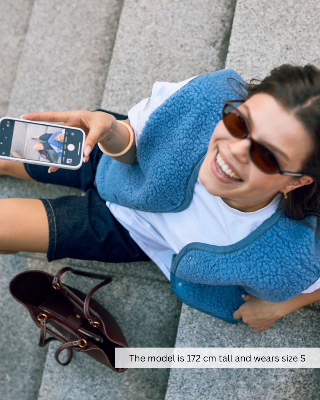 Woman relaxing outdoors in a blue merino wool vest, breathable merino wool vest for casual outfits